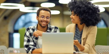 Cyber hygiene — Two colleagues collaborating at a laptop in a casual office setting